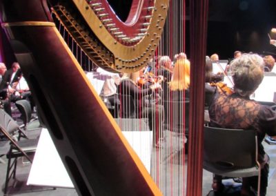 A large harp in a concert hall performed by SoCal Philharmonic.
