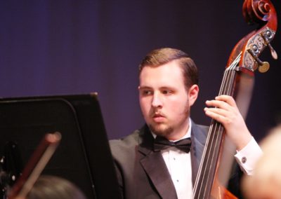 A man in a tuxedo playing a cello for the SoCal Philharmonic.