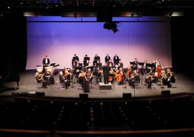 SoCal Philharmonic performing on stage in a large auditorium.