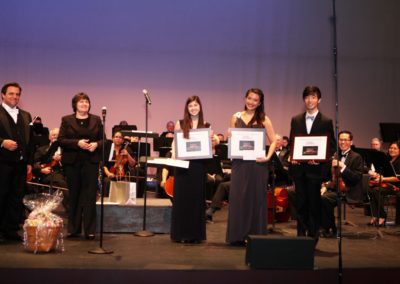 A group of people from the SoCal Philharmonic standing on stage holding trophies.