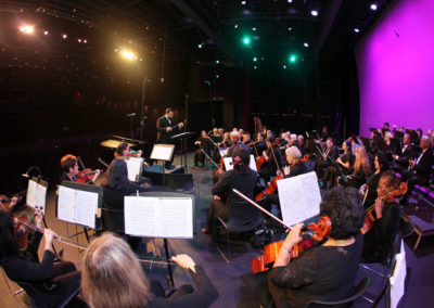 Symphony orchestra on stage with SoCal Philharmonic conductors and musicians.