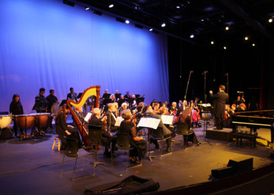 A group of people on stage with a conductor performing as the SoCal Philharmonic.