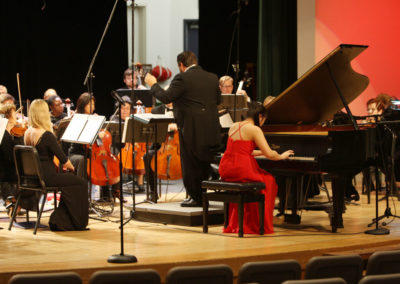 A woman in a red dress attending a SoCal Philharmonic concert.